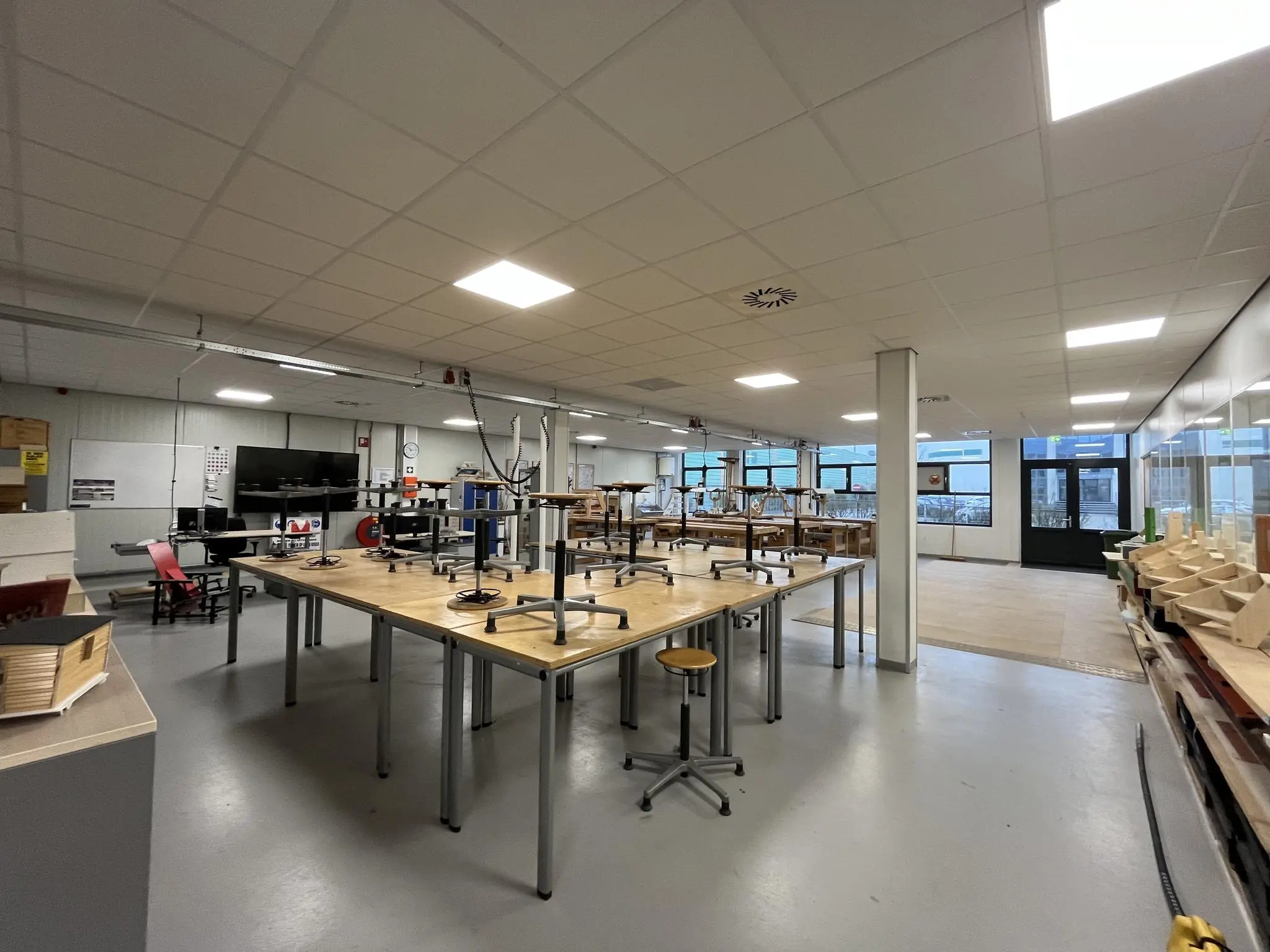 Lokaal met opgestapelde stoelen op werktafels in een praktijkruimte aan de Niels Bohrweg.